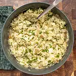 Creamy potato salad garnished with chopped herbs.