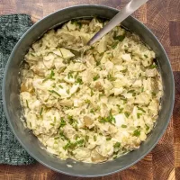 Creamy potato salad garnished with chopped herbs.