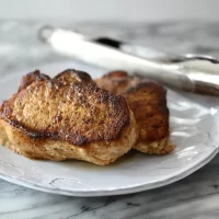 Golden-brown, seasoned grilled chicken thighs on a white plate.