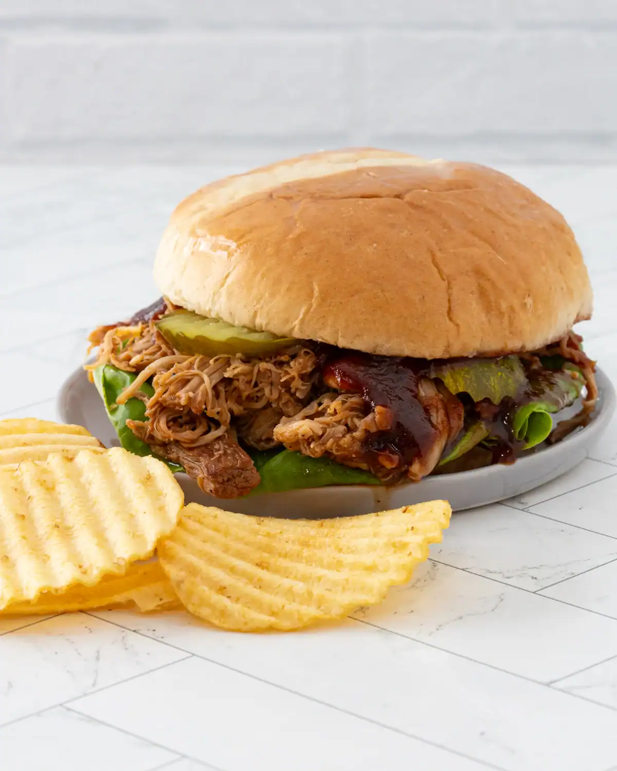 Slow-cooked pulled pork sandwich with barbecue sauce and pickles.