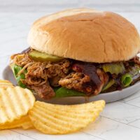 Instant Pot pulled chicken sandwich with pickles and bbq sauce.
