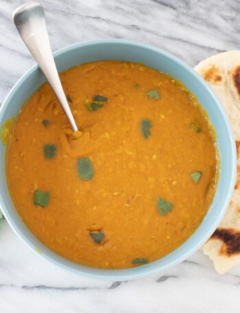 instant pot red lentil dal in a bowl with naan bread on the side