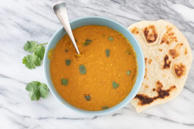 instant pot red lentil dal in a bowl with naan bread on the side