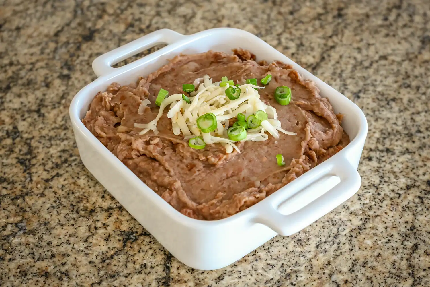 Refried beans in a square bowl.