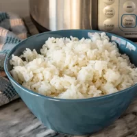 Steamed white rice in a blue bowl on a kitchen counter.