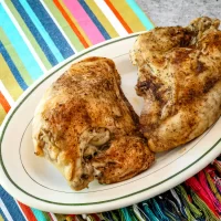 Baked chicken thighs with seasoned crispy skin on a white platter.