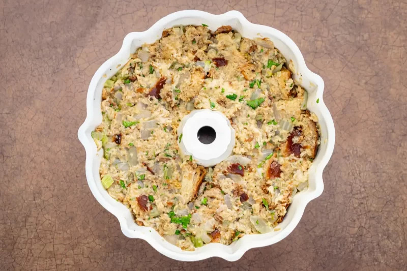 Creamy tuna casserole with chopped vegetables in a white baking dish.