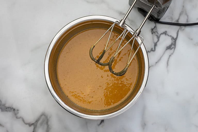 Creamy caramel sauce in a metal bowl with beaters.