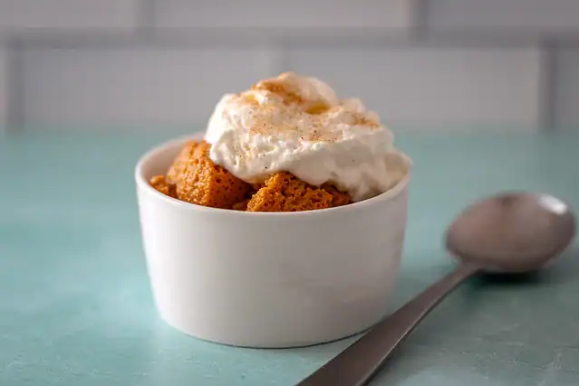 A small bowl of Instant Pot cooked sweet potato pudding with whipped cream.