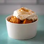 Homemade spice cake chunks topped with whipped cream and a dusting of cinnamon.
