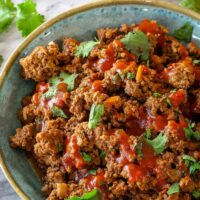 A bowl with Instant Pot taco meat, with taco shells and cilantro on the side.