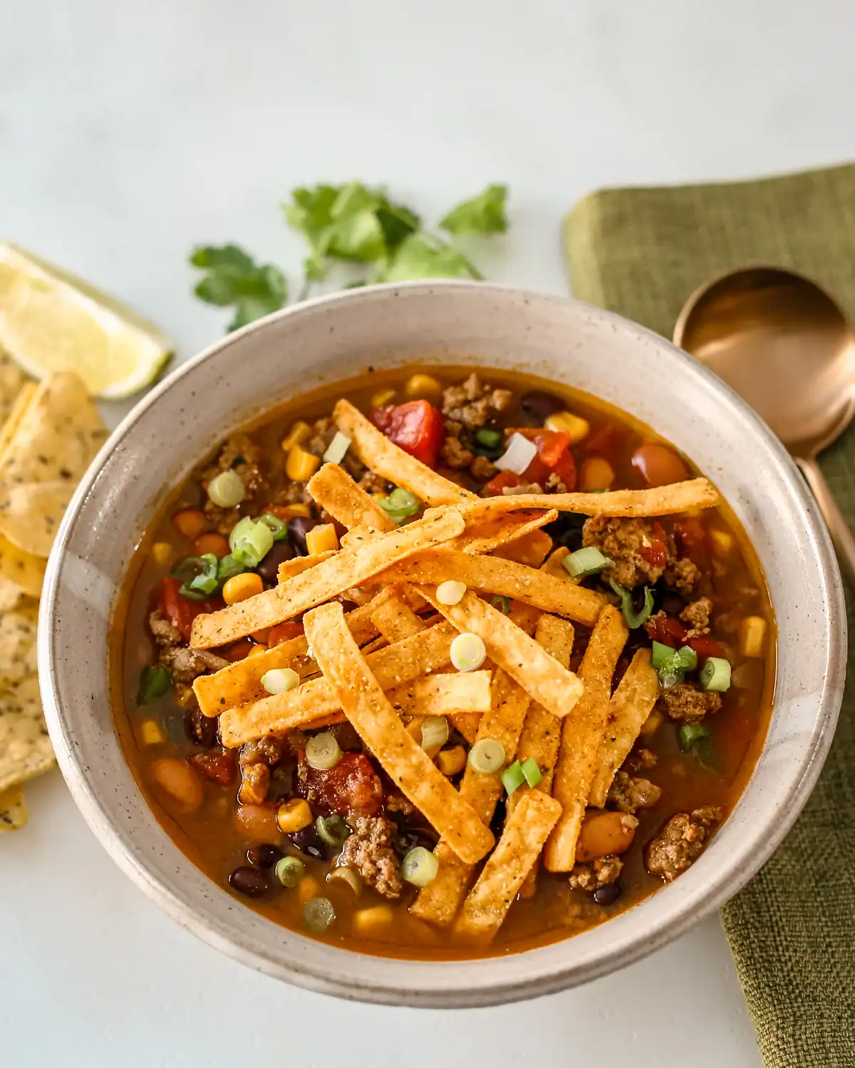 Bowl of beef chili with shredded cheese and green onions.