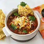 Recommendations, chili, with shredded cheese, Garnished with cilantro and tortilla chips, Hearty beef chili with vegetables served in a white bowl.