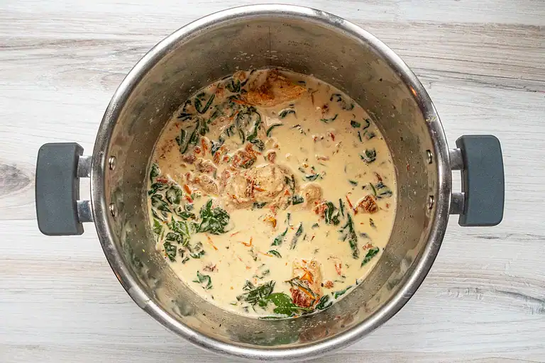 Creamy soup with vegetables and herbs in a stainless steel pot.