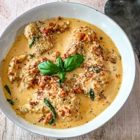 Creamy chicken curry garnished with fresh basil leaves and sliced chili peppers.