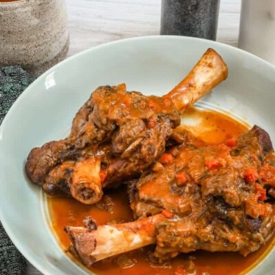 Braised beef shank with rich tomato sauce on a white plate.