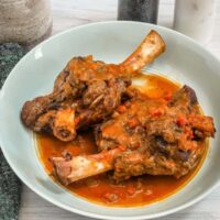 Slow-cooked lamb shanks in hearty stew with vegetables and savory sauce.