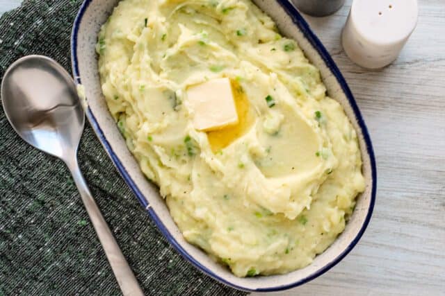 Creamy mashed potatoes with butter in a blue dish.