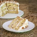 italian cream cake sliced on a plate with the whole cake in the background