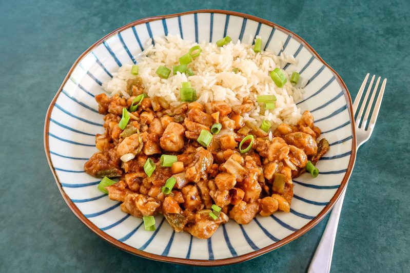 kung pao chicken with rice on the side and garnished with green onions