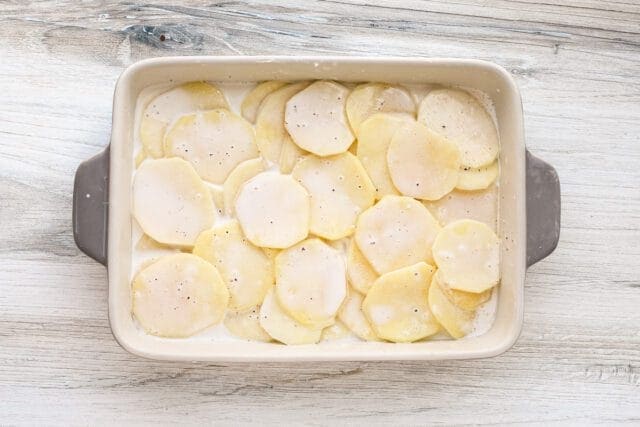 Raw sliced potatoes arranged in a baking dish.