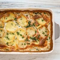 Creamy potato casserole with crispy browned edges and fresh herbs.