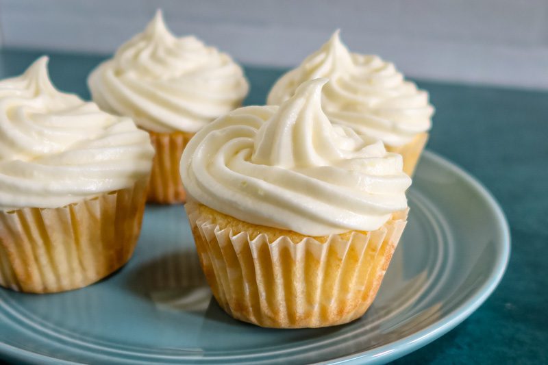 plate of cupcakes topped with lemon cream cheese frosting