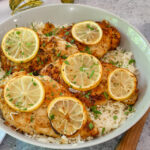 lemon pepper chicken in serving dish with lemon slices