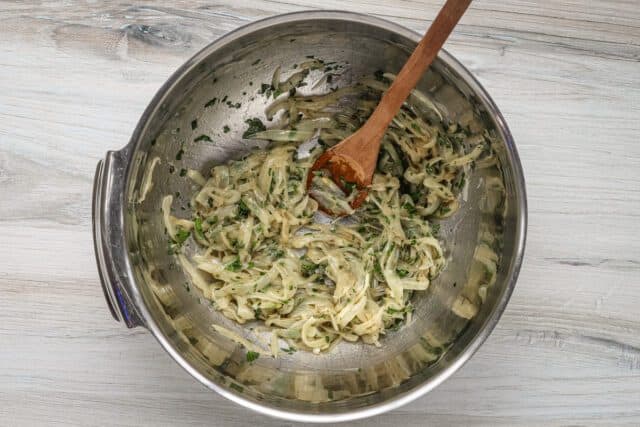Lyonnaise potato prep: the sautéed onions mixed with the herbs and grated garlic, in a large bowl.