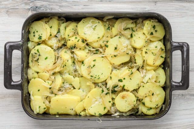 Creamy scalloped potatoes with cheese and herbs in a baking dish.