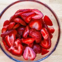 Fresh sliced strawberries in a glass bowl.