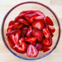 Fresh sliced strawberries in a glass bowl.