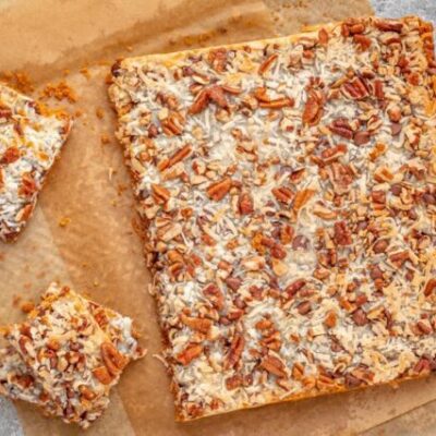 baked magic cookie bars on parchment paper, sliced