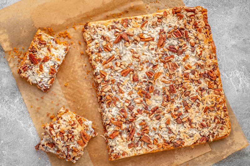 baked magic cookie bars on parchment paper, sliced