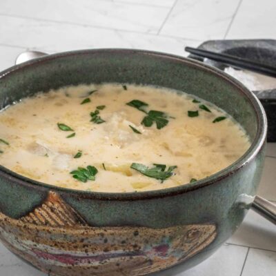 Creamy soup with herbs in a dark green bowl.