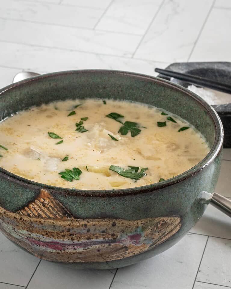 Creamy soup with herbs in a dark green bowl.
