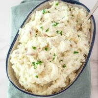 Creamy mashed potatoes with parsley garnish.