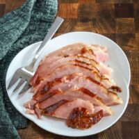 Sliced maple and brown sugar glazed ham on a serving platter.