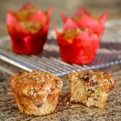 Fresh baked muffins with crumb topping and chocolate chips on a granite countertop.