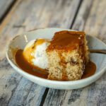 maple walnut cake with ice cream and caramel sauce in a dessert dish