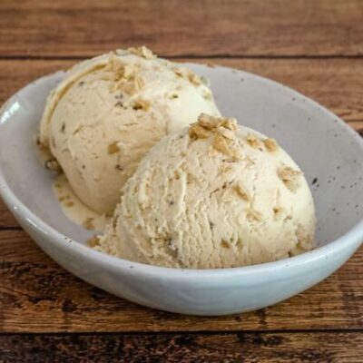 maple walnut ice cream in a bowl with maple flakes garnish