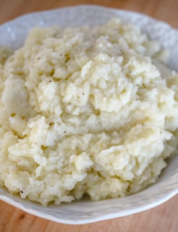 A bowl of fluffy mashed cauliflower made with butter, cream, garlic, and seasonings.