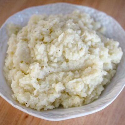 A bowl of fluffy mashed cauliflower made with butter, cream, garlic, and seasonings.