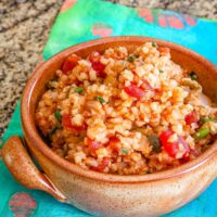 A bowl of Mexican cauliflower rice with tomatoes, green onions, and seasonings.