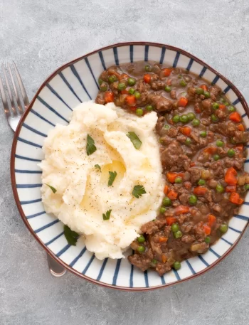 A plate of mince and tatties, mashed potatoes and ground beef in gravy.