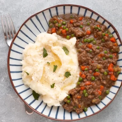 Tender beef stew with carrots and peas served with creamy mashed potatoes.