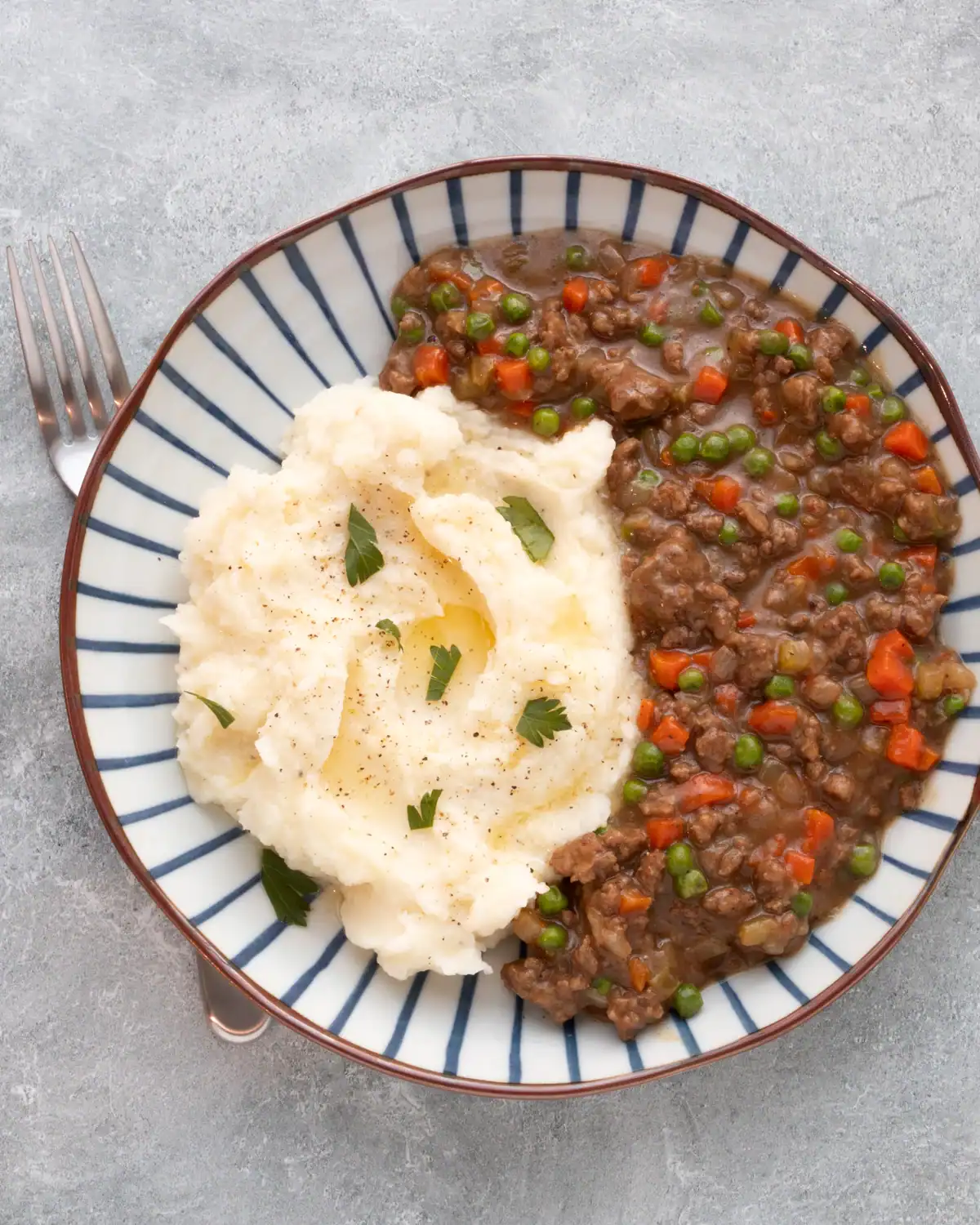 Tender beef stew with carrots and peas served with creamy mashed potatoes.