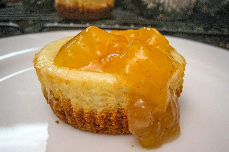 A delicious mini cheesecake on a plate with peach topping.