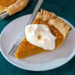 A slice of sweet potato pie with whipped cream garnish.
