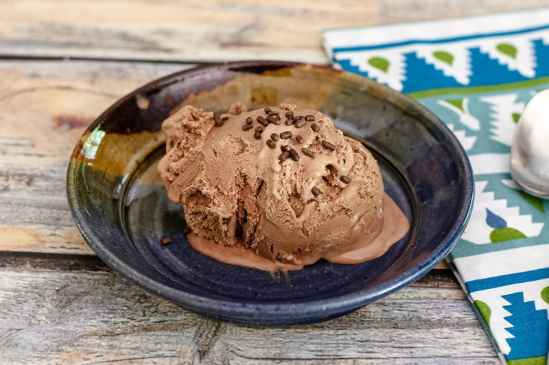 A scoop of mocha ice cream garnished with chocolate jimmies.